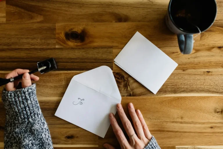 Mãos a escrever uma carta sobre uma mesa de madeira