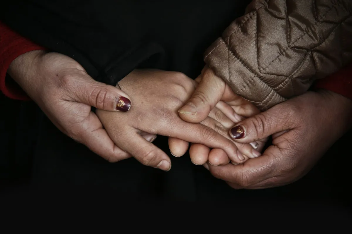 Mãos entrelaçadas de duas pessoas, gesto de cuidado