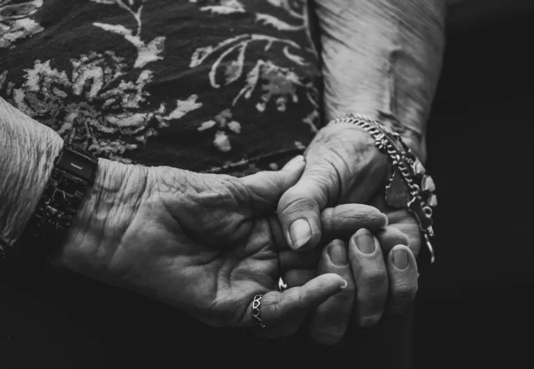 Mãos de uma senhora idosa nas mãos de uma familiar mais nova