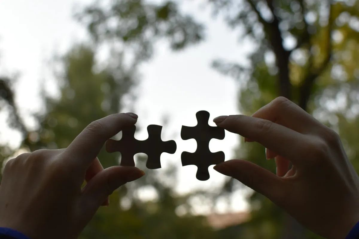 Mãos a juntar duas peças de um puzzle
